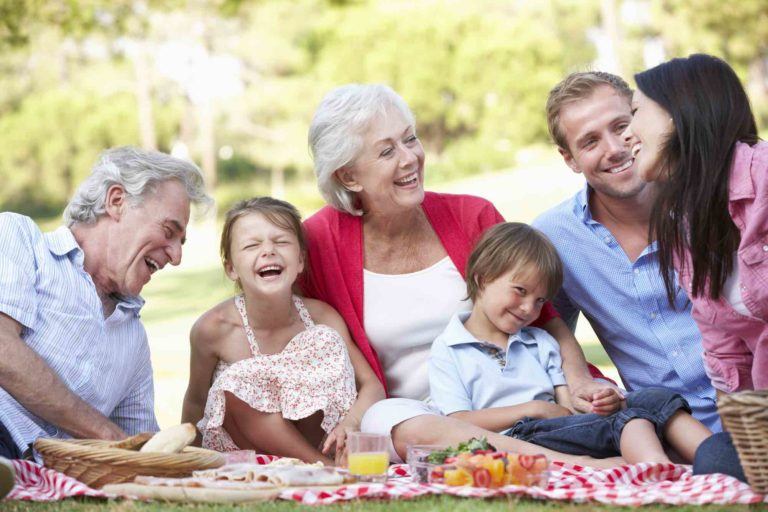 Familie sitzt im Grass und lacht